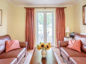 a living room with two couches and a table with a vase of flowers at Edlington Hall Cottage in Edlington