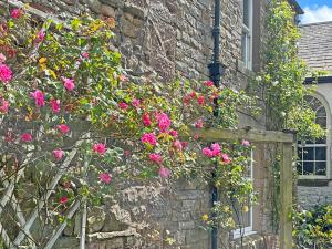 a stone building with pink flowers growing on it at Clifford Courtyard in Kirkby Stephen