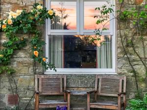 two chairs sitting in front of a window with flowers at Clifford Courtyard in Kirkby Stephen