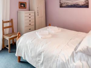 a bedroom with a white bed with a chair and a dresser at Clifford Courtyard in Kirkby Stephen