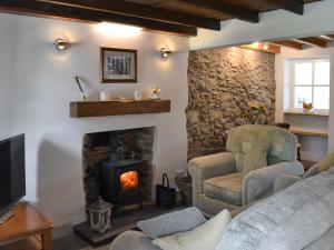 a living room with a stone fireplace and two chairs at Ty Bobbet in Amlwch