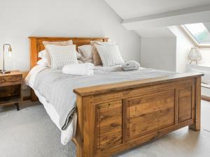 a bedroom with a large wooden bed with pillows at Bridge Cottage - Ukc9516 in Sheepwash