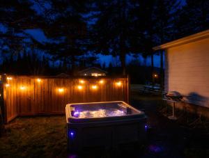 a hot tub with lights in a backyard at night at WOW Chalet Boho - Charlevoix Spa Firepit and BBQ in Saint-Tite-des-Caps +33 photos