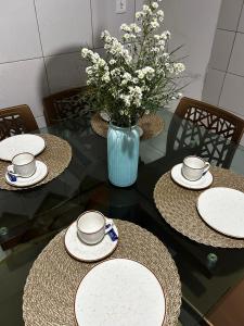 a table with three plates and a vase with flowers at Garanhuns casatres123 in Garanhuns +17 photos