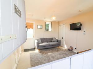 a living room with a couch and a television at Coach House in Beaworthy +8 photos