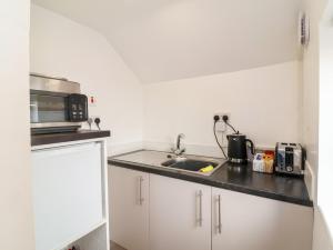 a small kitchen with a sink and a microwave at Coach House in Beaworthy