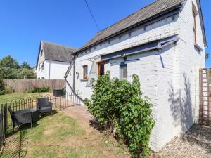 a white brick house with a bench in a yard at Coach House in Beaworthy