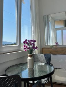 a glass table with a vase of purple flowers on it at Apartman DMA in Tivat