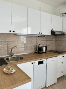 a kitchen with white cabinets and a plate of food on a counter at Apartman DMA in Tivat +13 photos
