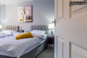 a bedroom with a bed with white sheets and a yellow pillow at Newly Refurbished Flat Parking 2 Bedrooms 4 Guests in Kenton