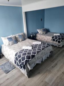 two beds in a room with blue walls at HOTEL LOYOLA in Coihaique