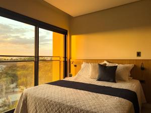 a bedroom with a bed and a large window at Moov Smart Home – Studios e Apartamentos por Temporada em Cuiabá in Cuiabá