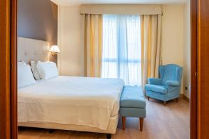 a hotel room with a bed and a blue chair at La Pieve Hotel in Chiampo +37 photos