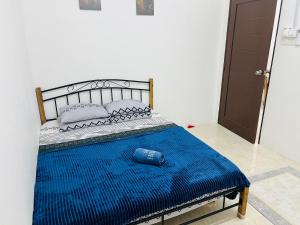 a bed in a room with a blue blanket on it at Sawaddi Homestay in Bukit Payong
