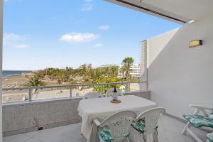 a balcony with a table and chairs and a view of the beach at A la Playa en San Agustín in Maspalomas