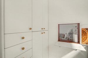 a white kitchen with a mirror and white cabinets at A la Playa en San Agustín in Maspalomas +17 photos