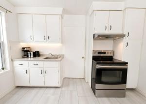 a kitchen with white cabinets and a black stove at Nature Chalet with Private Spa & Firepit in Saint-Tite-des-Caps