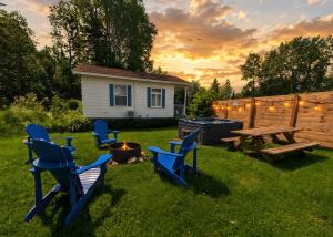 a backyard with blue chairs and a picnic table and a grill at Nature Chalet with Private Spa & Firepit in Saint-Tite-des-Caps +30 photos
