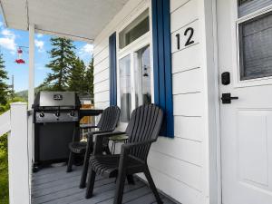 a porch with two chairs and a grill at Nature Chalet with Private Spa & Firepit in Saint-Tite-des-Caps