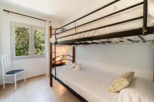 a bedroom with two bunk beds and a chair at Villa Casa Blanca Carbo by Sealand Villas in Cala de Sant Vicenc +24 photos