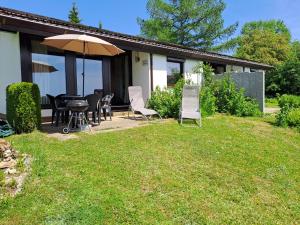 a patio with a table and chairs and an umbrella at Ferienhäuser Meiß - Feriendorf Öfingen Schwarzwald in Öfingen