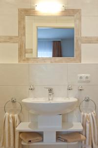 ein Badezimmer mit einem Waschbecken, einem Spiegel und Handtüchern in der Unterkunft Gästehaus Kerschbaum in Grainau