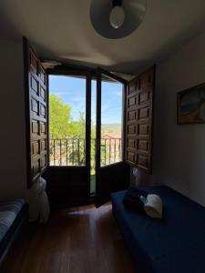 a room with two beds and a balcony with windows at Casa Nectarius in Cifuentes