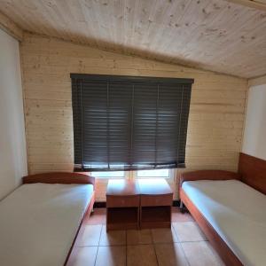 a room with two beds and a window with blinds at Rusałka Domki Rodzinne in Rudno