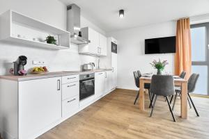 a kitchen with white cabinets and a dining room table at Enzian by Mountain ways in Loučná pod Klínovcem