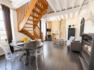 a living room with a table and a staircase at Apt duplex ou plain pied tout confort plein centre ville Bayeux proche commerces, restaurants, avec terrasse privative ou jardin commun aménagé clos, parking gratuit à proximité, proche plages du débarquement in Bayeux