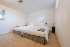 a white bedroom with a large white bed and wooden floors at 椿森コムナStay in Chiba