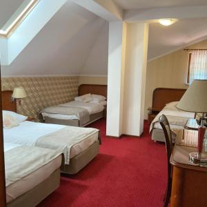 a hotel room with two beds and a red carpet at Hotel - Dworek Tryumf in Księżyno +101 photos