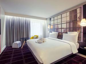 a hotel room with a large white bed and a window at Mercure Paris la Défense Grande Arche in Nanterre +78 photos