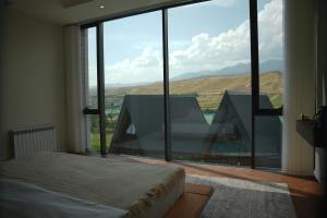 a bedroom with a bed and a large glass window at August Suites & Chalets in Khŭjakent Bekati