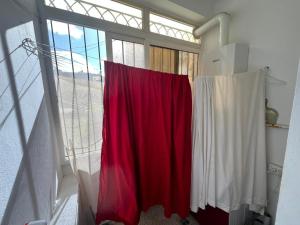 a red and white curtain in a room with a window at Modern Flat , Master Suite , Ain Zaghouan in El Aouina Station