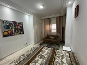 a living room with a couch and a painting on the wall at Modern Flat , Master Suite , Ain Zaghouan in El Aouina Station