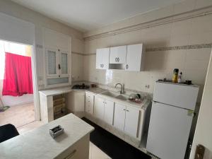 a kitchen with white cabinets and a white refrigerator at Modern Flat , Master Suite , Ain Zaghouan in El Aouina Station
