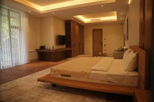 a bedroom with a large bed and a television at August Suites & Chalets in Khŭjakent Bekati
