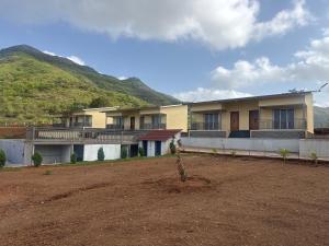 a house with a hill in the background at Jashoda Dham Agro Tourism in Pune
