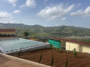 a swimming pool on top of a house with mountains at Jashoda Dham Agro Tourism in Pune +16 photos