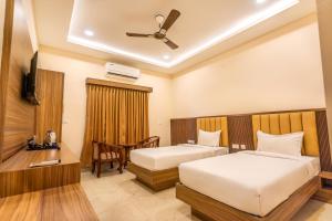 a hotel room with two beds and a television at Hotel Saesha International in Rāmeswaram