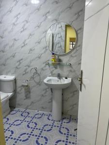 a bathroom with a sink and a mirror and a toilet at Galle subalbe in Pikine
