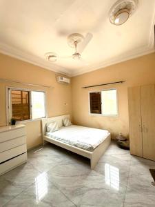 a bedroom with a bed and a dresser and two windows at KMR Apartment - Sira in Sere Kunda