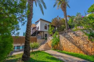 a house with palm trees and a stone wall at Villa Elfuze in Kalkan