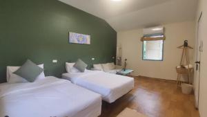 a bedroom with two beds and a green wall at Laena Homestay in Ko Yao Noi