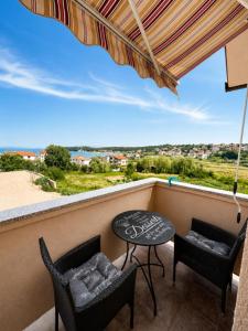 a balcony with two chairs and a table and an umbrella at Apartments Marina in Lopar