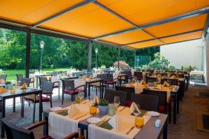 a restaurant with tables and chairs with yellow ceilings at Parkhotel Hohenfeld Münster in Münster