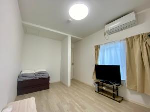 a living room with a flat screen tv and a window at Guest House TETSU in Oshima