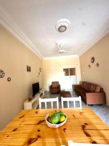 a living room with a wooden table with a bowl of fruit at KMR Apartment - Sira in Sere Kunda