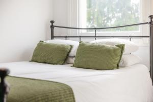 a bed with green and white pillows and a window at The Green Man in Dunchurch